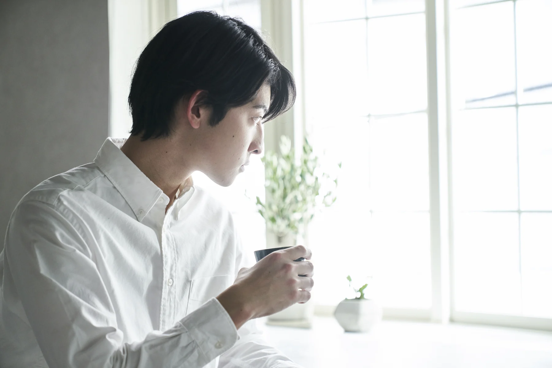 朝の自然光の中でコーヒーを楽しむ男性